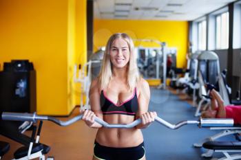 Young smiling girl in the gym with bar