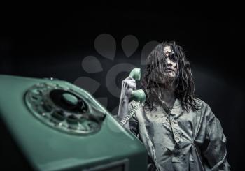 Portrait of the horror zombie girl calling by telephone. Scary