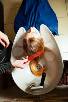 Hairdresser washing young woman's hair in salon. Hair care.