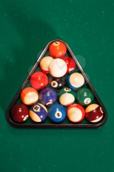 Balls in a pool triangle on the table. Green cloth