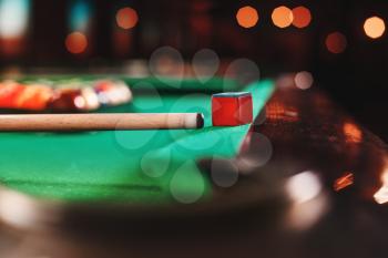 Cue and chalk on a pool table. Billiard balls in triangle on the background.