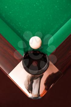 Above view on white billiard ball opposite to a pocket. Angle of the billiard table.