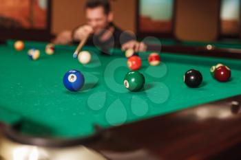 Player is going to drive a sphere into a billiard pocket. View from a corner of billiard table.