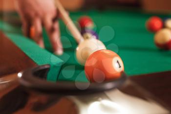 Male hand beats a sphere. Blur billiard balls on the background.