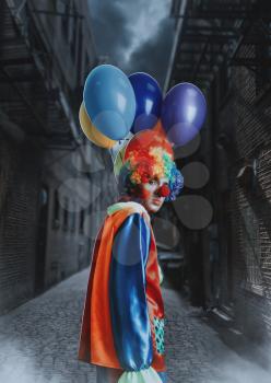Clown with a bunch of colorful air balloons standing in night alley.