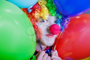 Smiling clown with a bunch of colorful air balloons. Humorous circus concept
