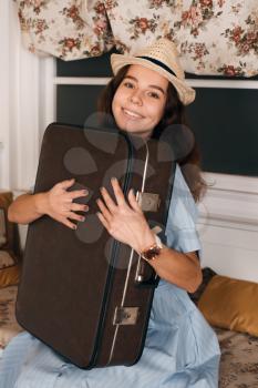 Young smiling woman with luggage sitting on sofa