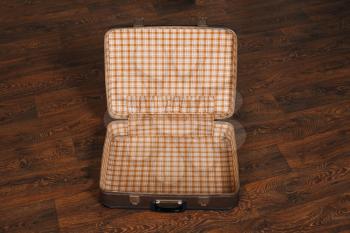 Top view of empty open retro suitcase on the wooden floor. Travel concept.
