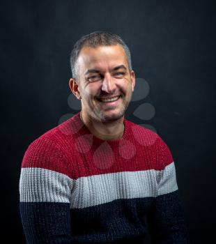 Portrait of smiling man in pullover isolated on  black background. Brutal unshaven handsome man in professional studio.