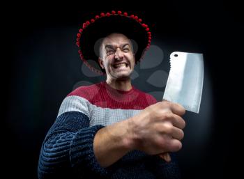 Angry psycho man in pullover and mexican sombrero with meat cleaver on black background. Crazy upset man waiting for his boss.  Office and corporate party concept.