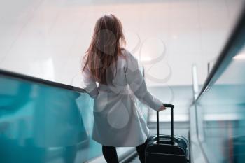 Young girl with suitcase down the escalator. Suitable for bus, railway, metro station or airport.
