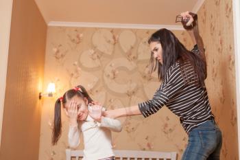 Strict mother hit her little daughter with belt.