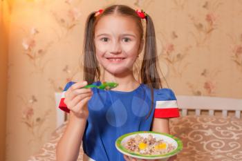 Smiling little girl with plate and spoon in hands.