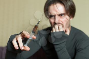 Depressed abuse addict man with syringe in hand.