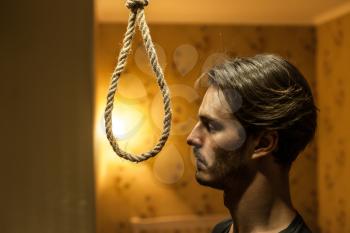 Desperate man preparing to commit suicide. Depressed man with a rope noose.