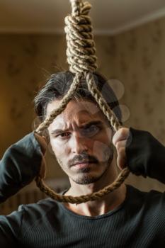 Desperate businessman preparing to commit suicide. Depressed man with a rope noose in his hands. 