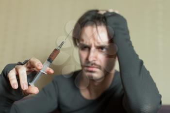 Depressed abuse addict man with syringe in hand.