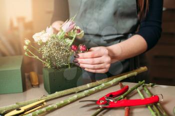 Florist at work closeup: woman creating decorative bouquet of flowers.