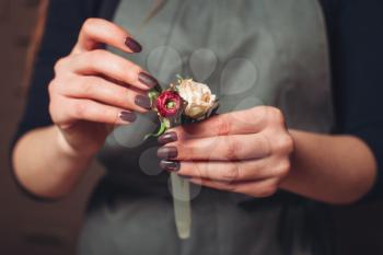 Female florist hands creating flower decoration closeup.
