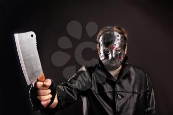 Murderer in hockey mask holding meat cleaver in hand, dark background