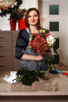 Female florist working with flowers while she made decorative bouquet.