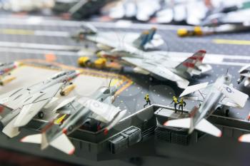 Miniature model of aircraft carrier runway with planes and people figures.