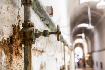Rusty water pipes of old prison. Blur hallway on background,