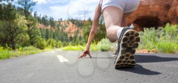 Runner feet in sport shoes running on mountain asphalt road closeup