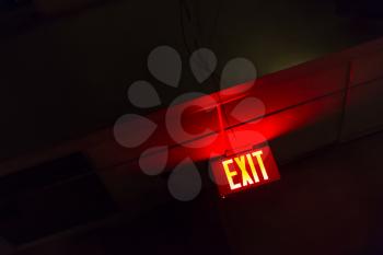 Illuminated red exit sign. Red light sign on the black background.