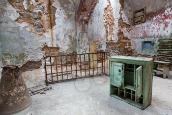 Jail interior with grunge rusty cell and brick walls.