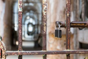 Door lock on rusty metal cell door in old prison. Blur jail hallway on background