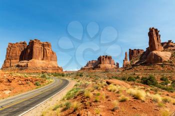 Road with red rocky mountains in the distance landscape in Arches National Park. Utah, USA