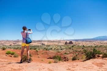 Young woman take pictures at monument valley. Blue sky on the background
