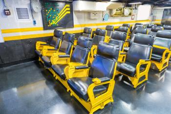 Aircraft carrier wardroom with yellow metal armchairs.Marine military museum