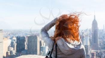 Young woman looking at the cityscape from observation deck. Blur city on background.