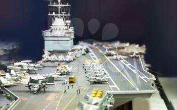 Miniature model of aircraft carrier on black background.
