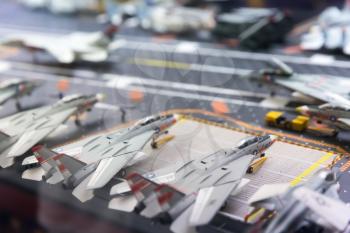 Miniature model of aircraft carrier runway with planes and people figures.