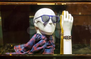 Male mannequin head in modern sunglasses and stylish scarf, dummy hand in leather bracelet. Vintage clothes in clothing shop.