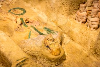 Archeological excavations of human burial. Figure and figurines on the background.