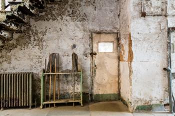 Old prison place with cleaning tools under staircase.