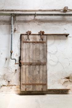 Inside old prison. Grunge wooden roller door in prison cell.