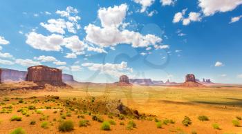 Desert, red sandstone mountains and blue cloudy sky at Monument Valley National Tribal Park, Navajo, Utah USA