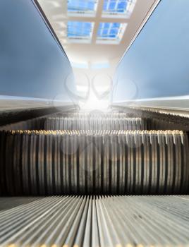 Modern escalator at sunny day with window at the background.