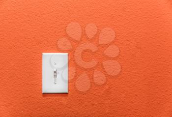 White power switch, turn on or turn off the power on orange wall.