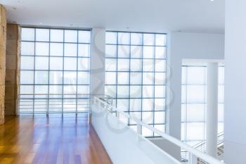 Balcony with wooden floor against glass block wall. White tones style.