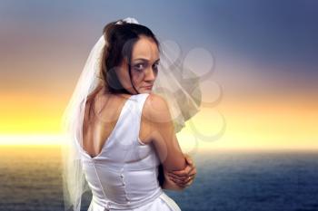 Tearful bride on the background of the sea and sunset