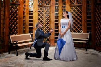 Groom proposing to the bride in a wooden gazebo. Newly married couple