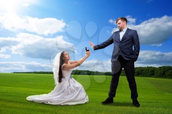 Beautiful bride makes offer to the groom against the background of a green meadow