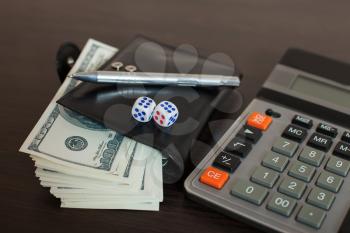 Wallet with dollars, pen and calculator on wooden table. Financial success sign