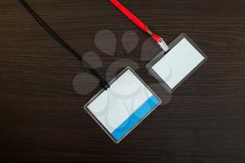 Two empty identification badges with black and red lanyard on wooden background